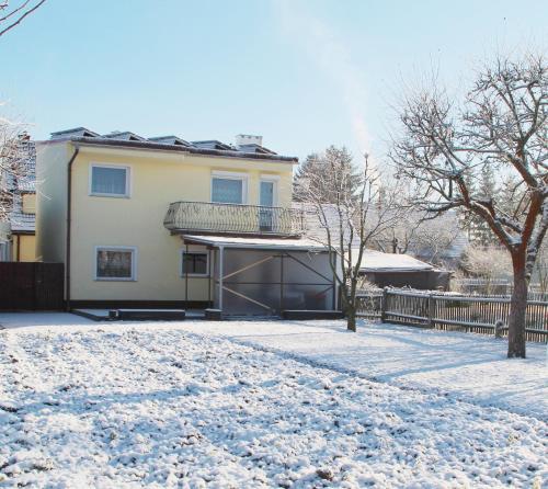 a house with snow on the ground next to a fence at Dom pod Górami in Mirsk