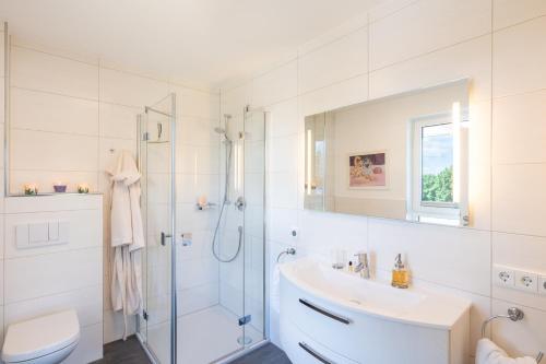 y baño blanco con lavabo y ducha. en Appartement "Traumzeit" mit Penthouseflair - Oase am Haff, en Garz