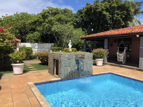 a swimming pool with a stone wall next to a house at Itacimirim Beach House in Itacimirim