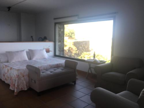 um quarto com uma cama, uma cadeira e uma janela em CASA LAS VISTAS em Fuencaliente de la Palma