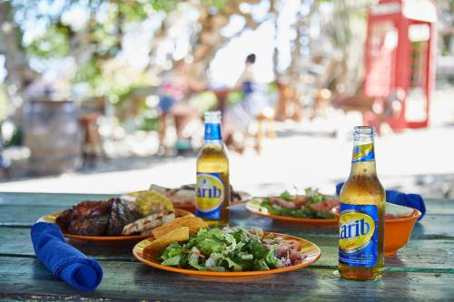 two bottles of beer and plates of food on a table at Pineapple Beach Club - All Inclusive - Adults Only in Willikies