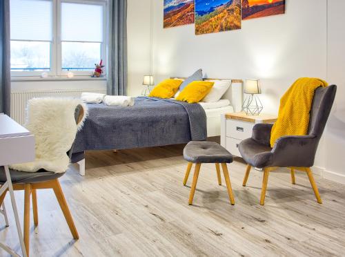 a bedroom with a bed with yellow pillows and two chairs at Apartament Rodzinny in Lesko