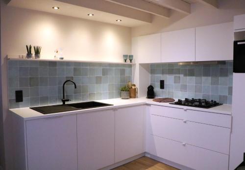 a kitchen with white cabinets and a sink at Maison des Étoiles in Aalst