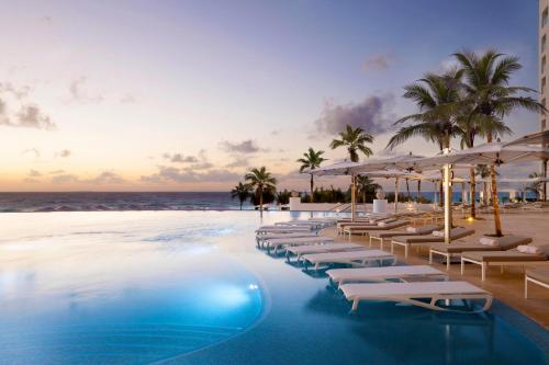 una piscina de hotel con sillas y sombrillas en la playa en Le Blanc Spa Resort Cancun Adults Only All-Inclusive, en Cancún