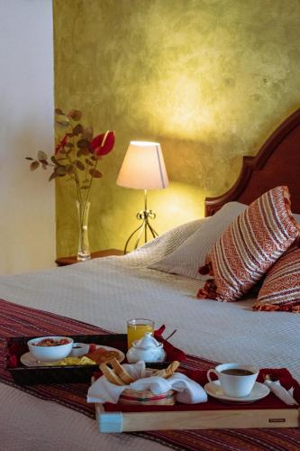 a bed with a tray of food and drinks on it at Hotel la Galería in Antigua Guatemala