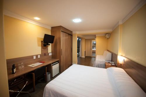 een hotelkamer met een bed, een bureau en een televisie bij Hotel Vinocap in Bento Gonçalves