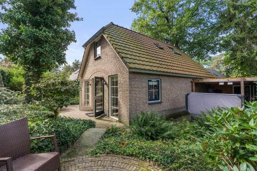 a small brick house with a garden in front of it at Vakantiehuis in het bos met jacuzzi en sauna in Lunteren
