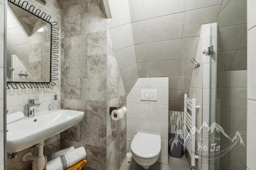 a white bathroom with a sink and a toilet at Bajeczna KoJa in Witów