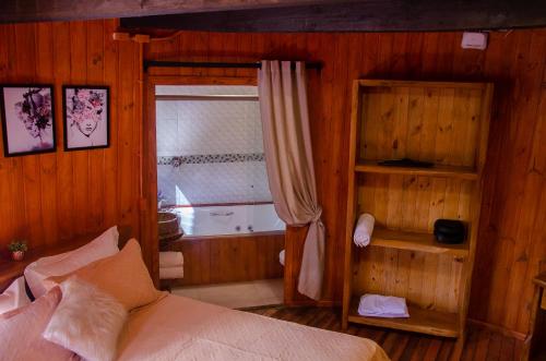 a bedroom with a bed and a window and a tub at Refúgio do Caracol Pipas e Chalés in Canela
