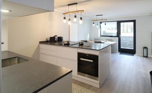 a kitchen with white cabinets and a black counter top at RMG Roses Apartments in Bad Kleinkirchheim