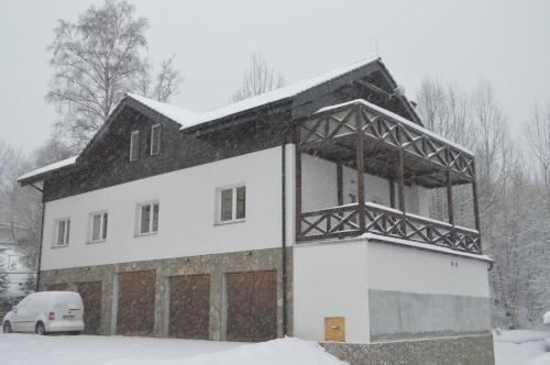 una casa en la nieve con un coche aparcado delante en Ager Apartments en Dolný Smokovec