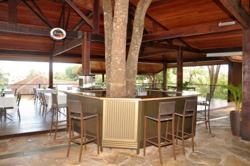 a restaurant with a bar with chairs and tables at Hotel Quadrado in Santa Bárbara