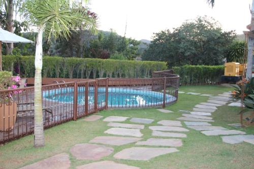 een zwembad in een tuin met een hek bij Hotel Quadrado in Santa Bárbara