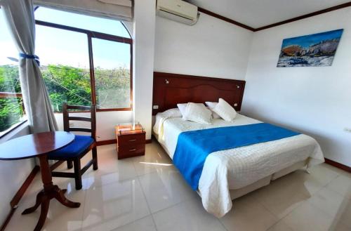 a bedroom with a bed and a table and a window at Galápagos Casa Playa Mann in Puerto Baquerizo Moreno