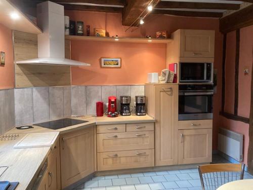 une cuisine avec des armoires en bois et un four à plaques de cuisson dans l'établissement Gîte SoleilMapou 12 personnes en Normandie près de Fécamp et Etretat, idéal grandes tribus, Zéro six soixante dix huit soixante treize trente six quatre vingt onze SoleilMapou large family house near Etretat 12 guests and 2 baby beds, à Ganzeville