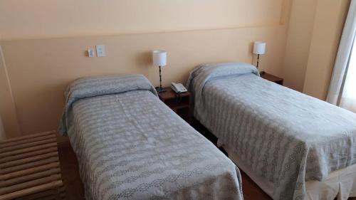 Habitación con 2 camas y mesa con lámparas. en LOWCOST MADRYN en Puerto Madryn