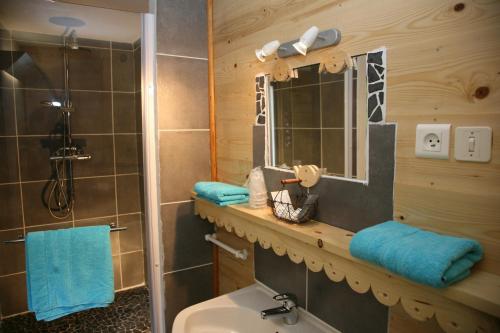 a bathroom with a sink and a shower with blue towels at Hôtel Le Glacier in Gourette