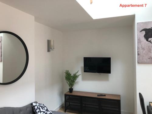a living room with a couch and a tv on a wall at Les appartements du quai in Dieppe