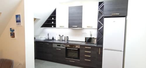 Una cocina con gabinetes negros y un refrigerador blanco. en Gabi Apartments Kopaonik - Kraljevi cardaci, en Kopaonik