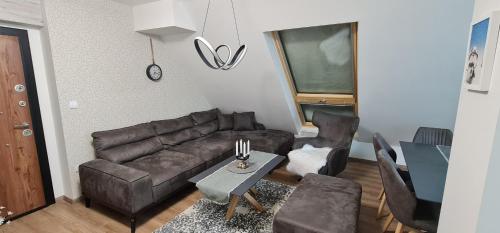 Una sala de estar con un sofá de cuero y una mesa. en Gabi Apartments Kopaonik - Kraljevi cardaci, en Kopaonik