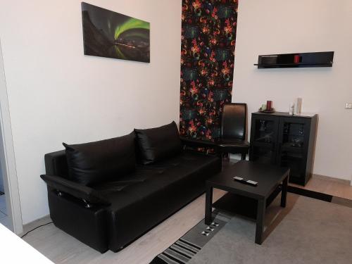 a living room with a black leather couch and a table at Wohnung "Stern" in Chemnitz