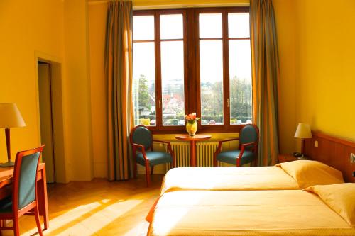 a hotel room with two beds and a table and a window at Le Cénacle in Geneva