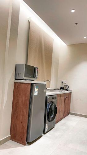 a kitchen with a washing machine and a microwave at سيتيز إن للشقق المخدومة in Yanbu