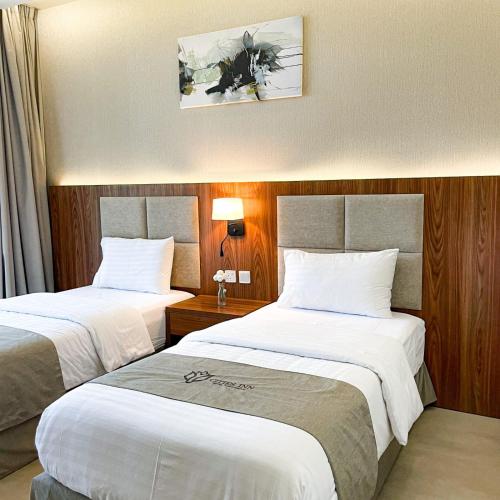 a hotel room with two beds with white sheets at سيتيز إن للشقق المخدومة in Yanbu