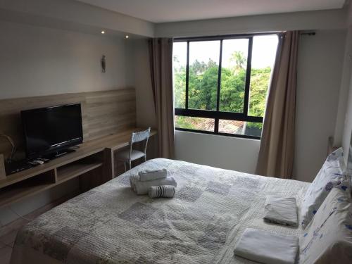 - une chambre avec un lit, une télévision et une fenêtre dans l'établissement Flat Praia do Cabo Branco - Casados para sempre!, à João Pessoa