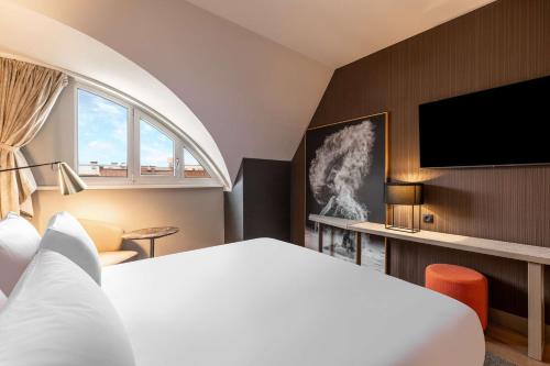 a hotel room with a bed and a flat screen tv at NH Collection Salzburg City in Salzburg