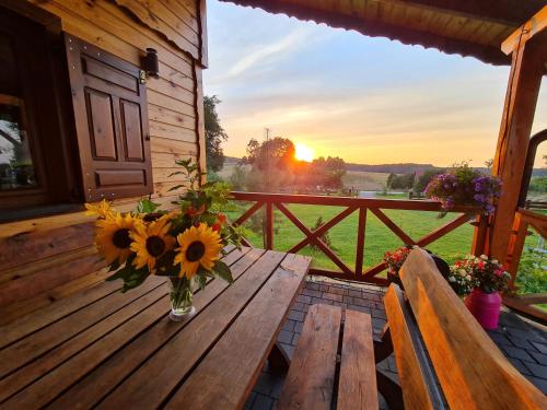 a vase of sunflowers on a wooden table on a porch at Siedlisko na Wzgórzu - Noclegi Agroturystyka - Borsuki in Sarnaki