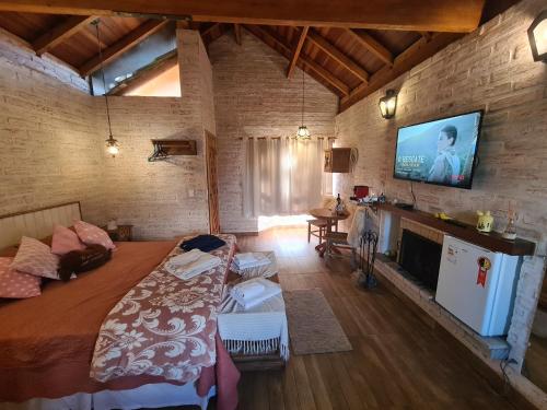 a bedroom with a bed and a tv on a brick wall at Pousada Canto do Sabiá in Monte Verde