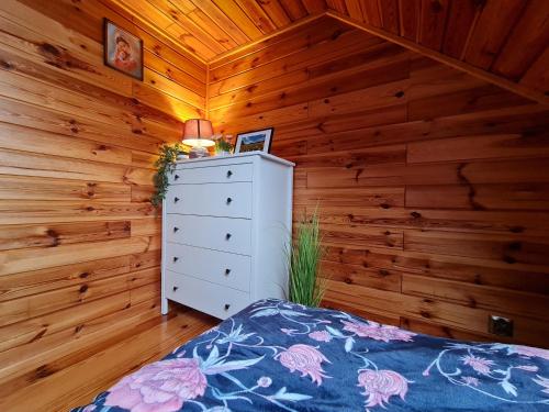 a bedroom with a bed and a dresser in a cabin at Siedlisko na Wzgórzu - Noclegi Agroturystyka - Borsuki in Sarnaki