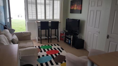 a living room with a couch and a tv at Sundown 127 Sandown Bay Holiday Centre Generous Ferry Saving! in Sandown