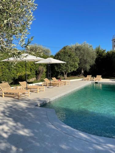 einen Pool mit Liegestühlen und Sonnenschirmen neben einem Pool in der Unterkunft Villa La Carpenée in Roquefort-les-Pins