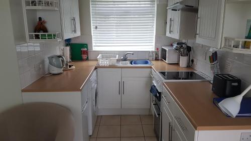 a kitchen with white cabinets and a sink at Sundown 127 Sandown Bay Holiday Centre Generous Ferry Saving! in Sandown