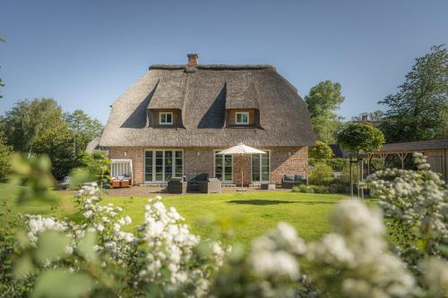 a thatch roofed house with a yard at Ferienhaus Koellers Hus in Sankt Peter-Ording