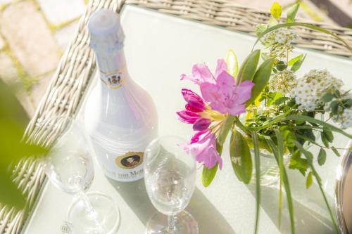 eine Flasche Wein, Gläser und Blumen auf dem Tisch in der Unterkunft Ferienhaus Koellers Hus in Sankt Peter-Ording
