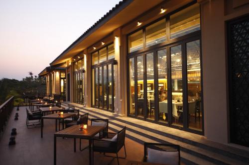 a restaurant with tables and chairs on a balcony at Raffles Hainan Clear Water Bay in Sanya
