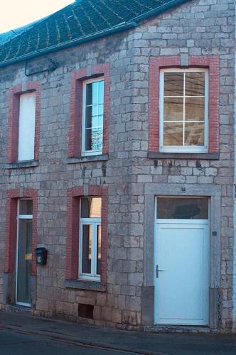 フィリップヴィルにあるLe Gîte de Zao avec billardの白いドアと3つの窓があるレンガ造りの建物