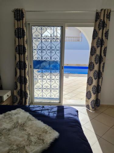 a bedroom with a bed and a door with a window at Kmi in Zarzis