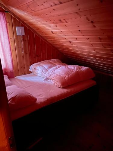 a bed in a wooden room with two pillows at Ski and Bike-In and Out in Hafjell