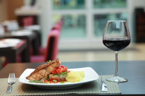 a plate of food and a glass of wine on a table at Mercure Hanoi La Gare Hotel in Hanoi