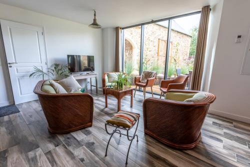 a living room with chairs and a couch and a tv at Les gîtes du Haut Pin in Calorguen