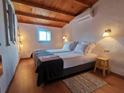 uma cama grande num quarto com tecto em madeira em Chão da Velha - Casas de Campo em Nisa