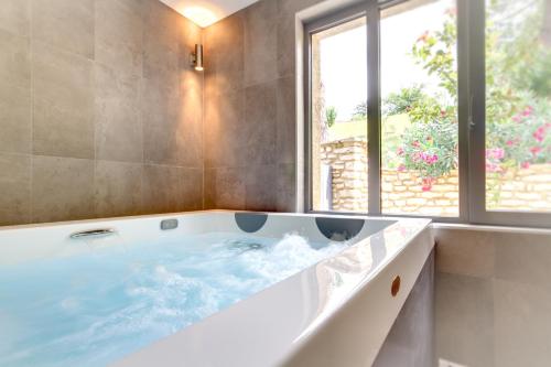 uma grande banheira numa casa de banho com uma janela em Le Florida Auberge contemporaine em Castéra-Verduzan
