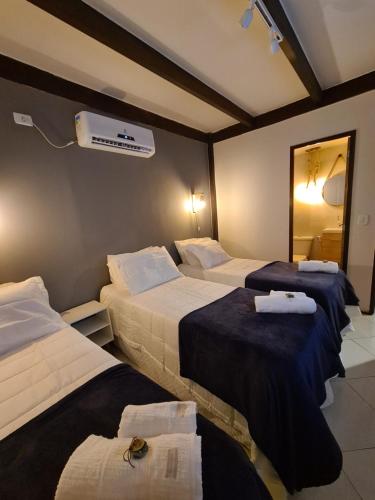 a hotel room with three beds and a fan at Pousada Estrela Cordel in Fernando de Noronha