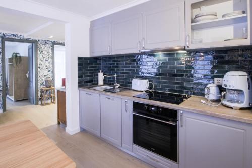 a kitchen with white cabinets and a black tile wall at Chalet Antoine serviced Apartments by Mirabeau in Zermatt