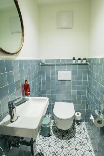 a blue tiled bathroom with a toilet and a sink at Chalet Antoine serviced Apartments by Mirabeau in Zermatt