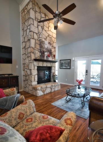 a living room with a stone fireplace and a table at Home On the Green in Salado